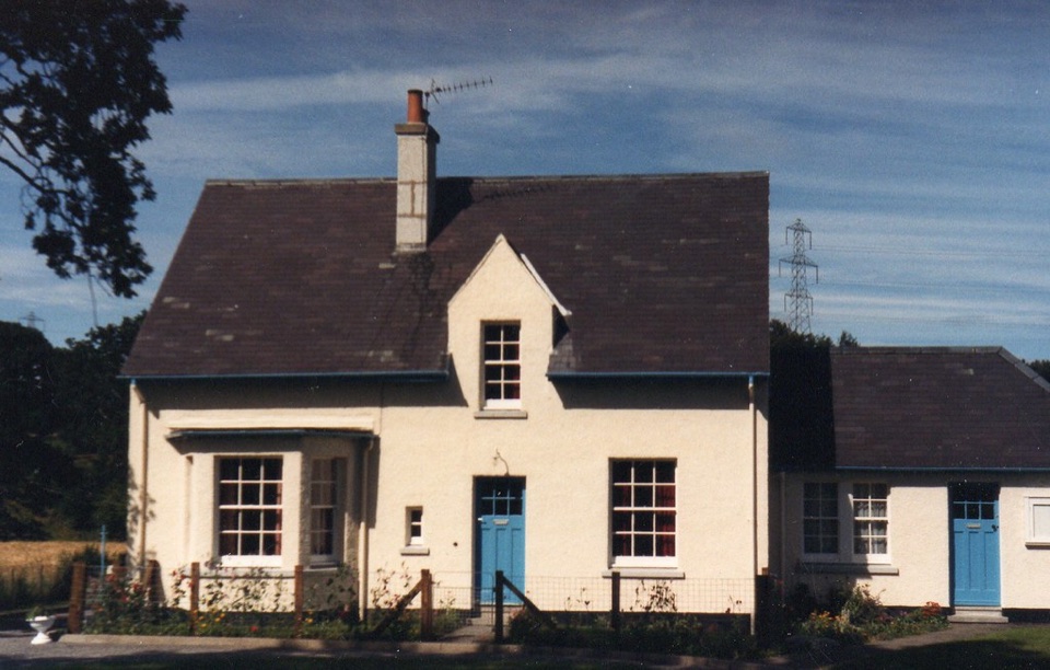A harled cottage with a slate roof and blue doors near Inverness