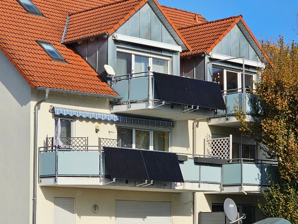 Two plug-in solar panels fixed to the balcony rails of a house