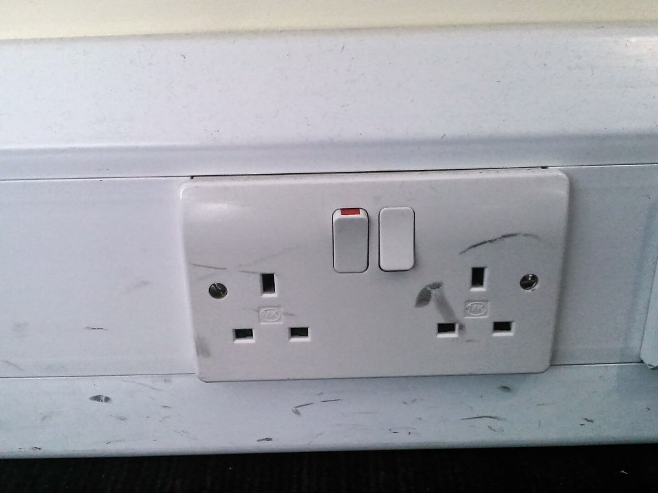 A white British double socket with its switches on a wall
